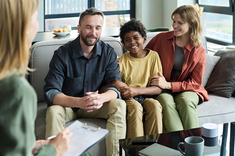 A family sitting together with a clinician in a counseling session.